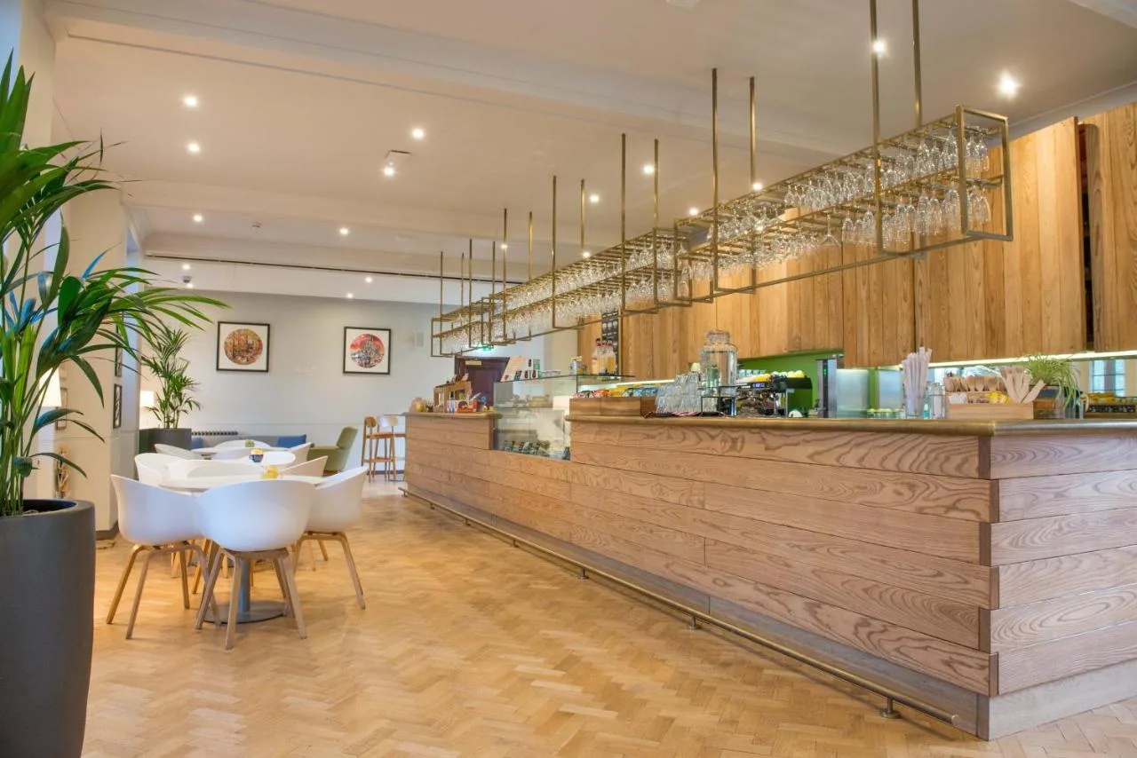 a restaurant with a counter with white chairs at West Court- Jesus College in Cambridge