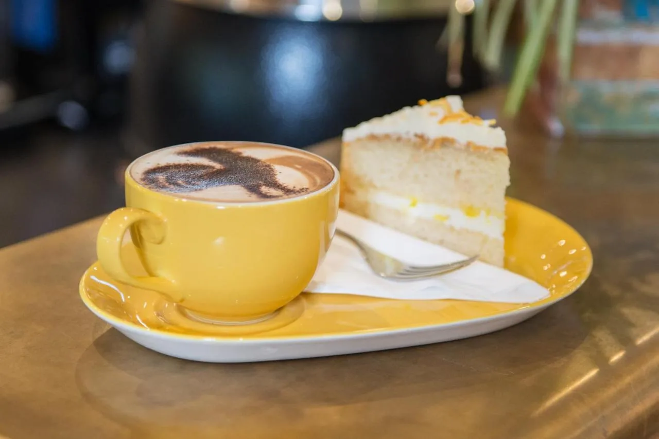 a cup of coffee and a piece of cake on a table at West Court- Jesus College in Cambridge